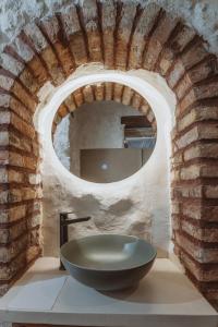 un bagno con lavandino a ciotola in un muro di mattoni di Pargas Distillery Suites a Párga