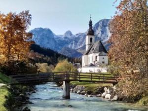 eine Kirche mit einer Brücke über einen Fluss mit einer Kirche in der Unterkunft Rossfeld Modern retreat in Berchtesgaden