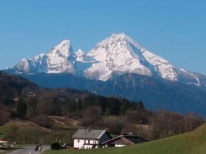 einen schneebedeckten Berg mit einem Haus im Vordergrund in der Unterkunft Rossfeld Modern retreat in Berchtesgaden