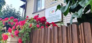 une clôture en bois avec des fleurs rouges devant un bâtiment dans l'établissement Aparthotel 3 ,, Cosy House Studio'' & Parking, à Kaunas