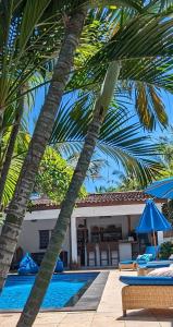 una piscina con due palme accanto a una casa di Indigo Bungalows a Gili Trawangan