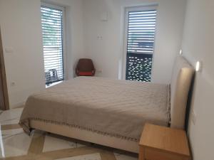 a bedroom with a bed and a chair and two windows at PALAR Apartment in Ljubljana