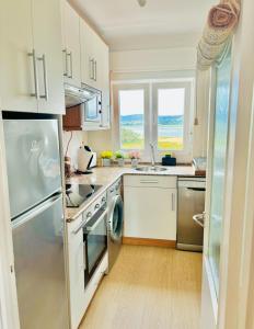 una cocina con armarios blancos y un aparato de acero inoxidable en APARTAMENTO el PUNTAL- LAREDO, en Laredo