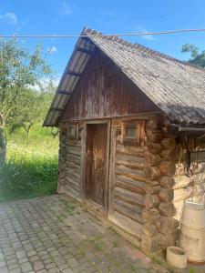 una baita di tronchi con una porta in legno in un campo di Nad Cheremoshem a Tyudov