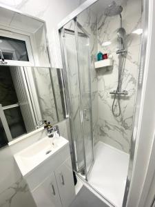 ein Bad mit einer Dusche und einem Waschbecken in der Unterkunft THE ROYAL BOUTIQUE REGENT LODGE bY LONDON , SLEEP 8 in London