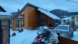 une maison enneigée avec une moto garée dans la neige dans l'établissement Kokhta Villa In Bakuriani, à Bakuriani