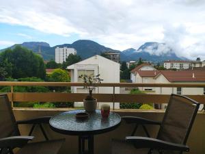 een tafel en stoelen op een balkon met uitzicht op de bergen bij Chambres dans appartement partagé in Grenoble