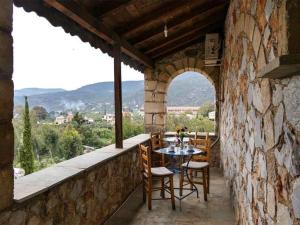 un patio con mesa y sillas en una pared de piedra en KASTRO AGGELIKI, en Kardhamili