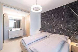 - une chambre avec un lit et un grand mur dans l'établissement Boutiquehotel Wörthersee - Serviced Apartments, à Velden am Wörther See