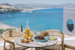 uma mesa com um prato de comida e um copo de sumo de laranja em Lindos Mare, Seaside Hotel em Líndos