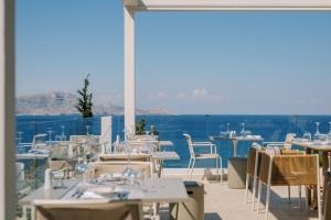 um restaurante com mesas e cadeiras e vista para o oceano em Lindos Mare, Seaside Hotel em Líndos