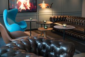 sala de estar con sofá de cuero y silla en Motel One Lübeck, en Lübeck