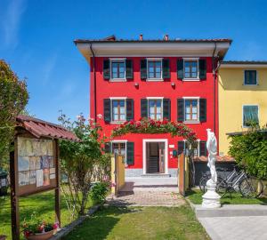 una casa roja con persianas negras y flores delante en B&B Il Giardino dei Poeti and Apartaments, en Lucca