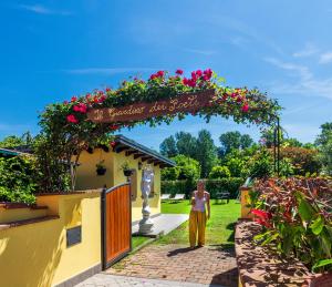 una mujer de pie bajo un arco con flores en B&B Il Giardino dei Poeti and Apartaments, en Lucca