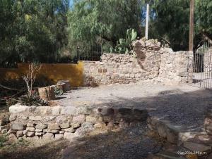 una pared de piedra en un patio con una valla en La Pirquita, en Tilcara