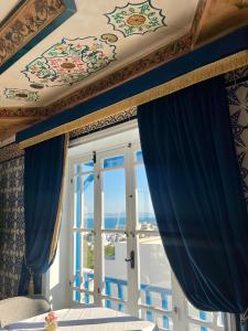 a bedroom with blue curtains and a window at La Menara Hotel & SPA in Sidi Bou Saïd