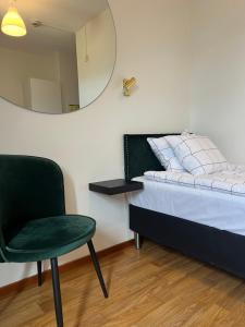 - une chambre avec une chaise verte et un miroir dans l'établissement Hotell City Karlshamn, à Karlshamn