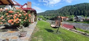 un giardino fuori da una casa con fiori e altalena di "Обійми гір"Котеджі a Jaremče