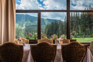 uma sala de jantar com mesa e cadeiras e uma grande janela em Wellness Hotel Šedý Vlk em Harrachov