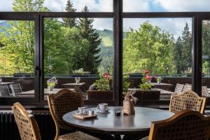 uma mesa e cadeiras num quarto com uma grande janela em Wellness Hotel Šedý Vlk em Harrachov