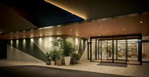 un hall avec des plantes en pot devant un bâtiment dans l'établissement Hotel Flora Funabashi, à Funabashi