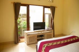 1 dormitorio con 1 cama, TV y ventana en Sekar Waru Homestay, en Sanur