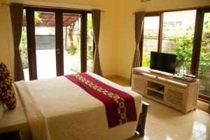 1 dormitorio con 1 cama y TV de pantalla plana en Sekar Waru Homestay, en Sanur