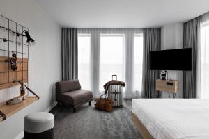 Habitación de hotel con cama, silla y TV en Moxy Lyon Airport, en Saint-Exupéry