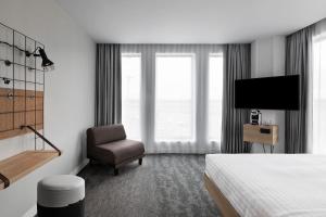 Habitación de hotel con cama y silla en Moxy Lyon Airport, en Saint-Exupéry