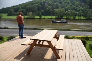 een man op een houten terras met een picknicktafel bij Le Paradis Mosan in Waulsort