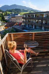 una mujer sentada en una silla sosteniendo una copa de vino en Hotel Planai by Alpeffect Hotels, en Schladming