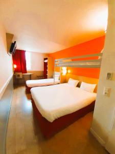 duas camas num quarto de hotel com paredes cor de laranja em B&B HOTEL Saint-Witz Roissy em Saint-Witz