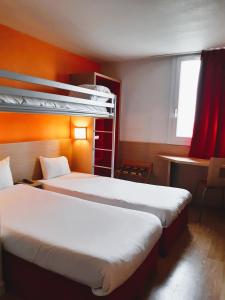 um quarto com 2 camas e uma secretária com uma janela em B&B HOTEL Saint-Witz Roissy em Saint-Witz