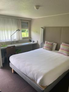 um quarto com uma grande cama branca e uma secretária em B&B HOTEL Saint-Witz Roissy em Saint-Witz