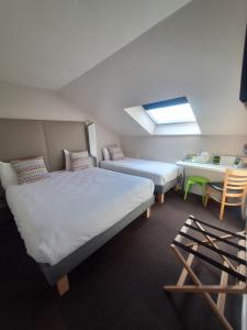 um quarto com duas camas e uma mesa e uma janela em B&B HOTEL Saint-Witz Roissy em Saint-Witz