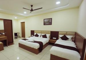 a bedroom with two beds and a ceiling fan at JKInn in Vellore