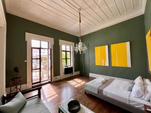 um quarto com paredes verdes, uma cama e um lustre em Thirty8 Heritage House em Chania