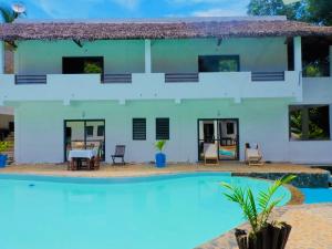 une villa avec une piscine en face de celle-ci dans l'établissement Hotel Océan Beach Sakatia, à Nosy Be