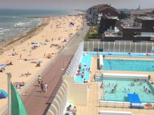 een groep mensen in een zwembad naast een strand bij "O'Dbark" - duplex 2 étoiles - à 100m de la plage in Courseulles-sur-Mer