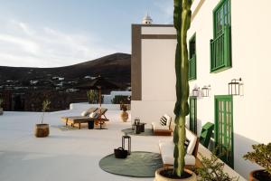 um pátio com cadeiras e uma palmeira num edifício em César Lanzarote Luxury Boutique Hotel - Adults Only em La Asomada