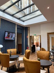 a lobby with tables and chairs and a skylight at Hotel Le Jacquemart in Dijon