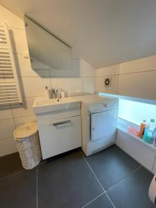 a white bathroom with a sink and a dishwasher at JZ apartamentai in Kelmė