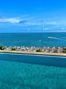 una piscina accanto a una spiaggia con sedie e ombrelloni di Hotel Ponta Plaza Conference & Spa a Budua