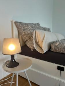 a lamp on a table next to a bed with pillows at Double Bed Apartment - Near Marienplatz in Stuttgart