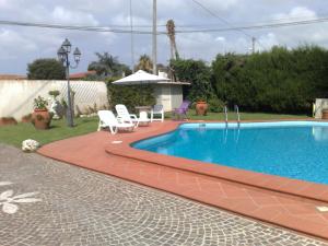 een zwembad in een tuin met stoelen en een parasol bij Casa Sirina in Terracina