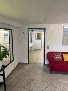 a living room with a red couch and a mirror at Hytte A in Gråsten