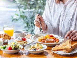 a woman sitting at a table with plates of breakfast food at Tokyu Stay Shimbashi - Ginza area in Tokyo