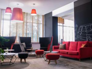 una hall con divano rosso, sedie e tavoli di ibis Styles Bielsko Biala a Bielsko-Biała