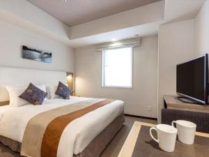 a hotel room with a bed and a flat screen tv at Tokyu Stay Shimbashi - Ginza area in Tokyo