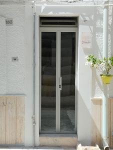 una puerta de cristal en una casa blanca con escaleras en Dimora Dioniso, en Polignano a Mare